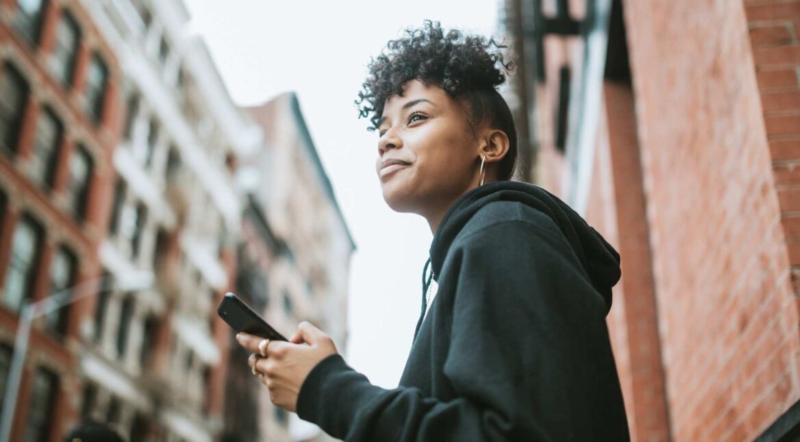 Junge Frau fügt am iPhone Kontakt den Favoriten hinzu.