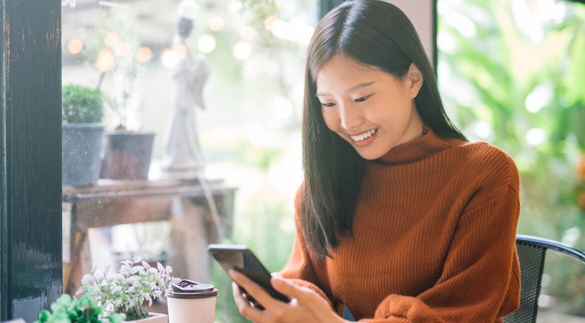 Junge Frau schaut am Handy in Google Maps rein.