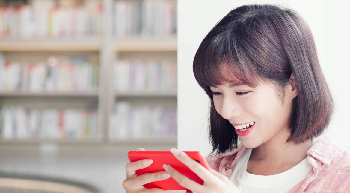 Junge Frau zockt PS4-Spiele am Smartphone.