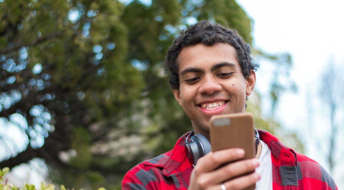 Junger Mann löst am Smartphone sein Twitter-Problem.