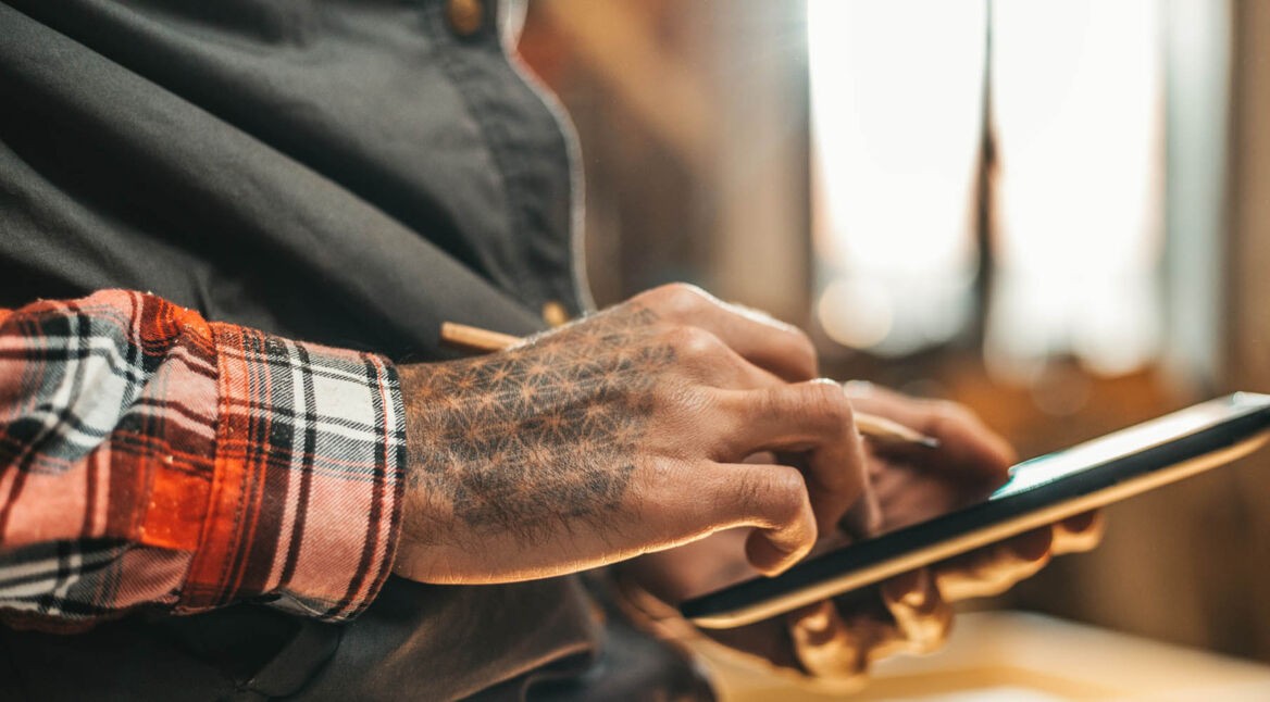 Junger Mann zockt das Kartenspiel Gwent am Smartphone.