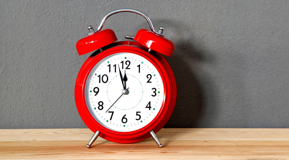 Ein roter Wecker steht auf dem Regal.