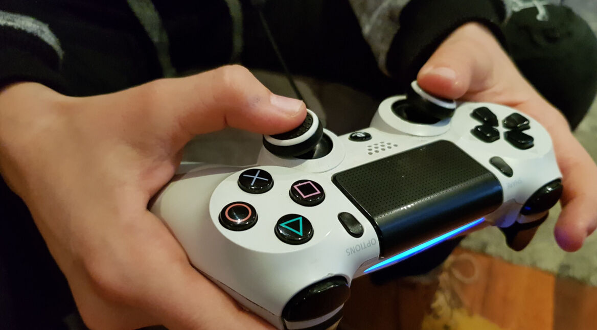 Hand hält weißen PlayStation-4-Controller.