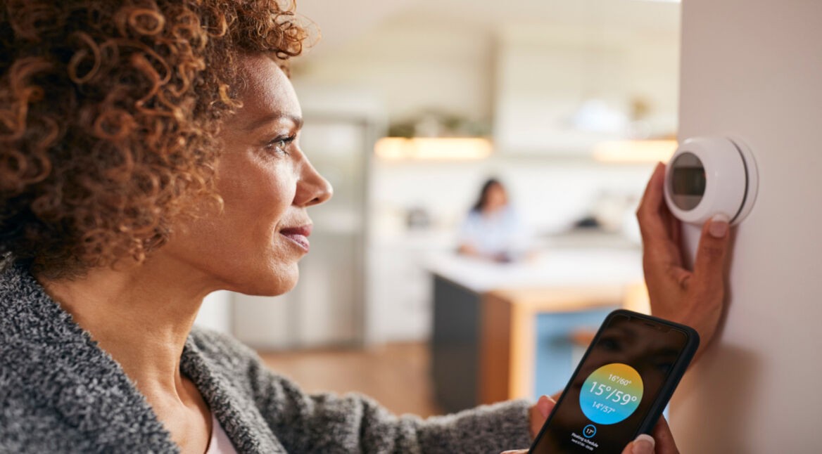 Eine Frau stellt einen smarten Thermostat ein.