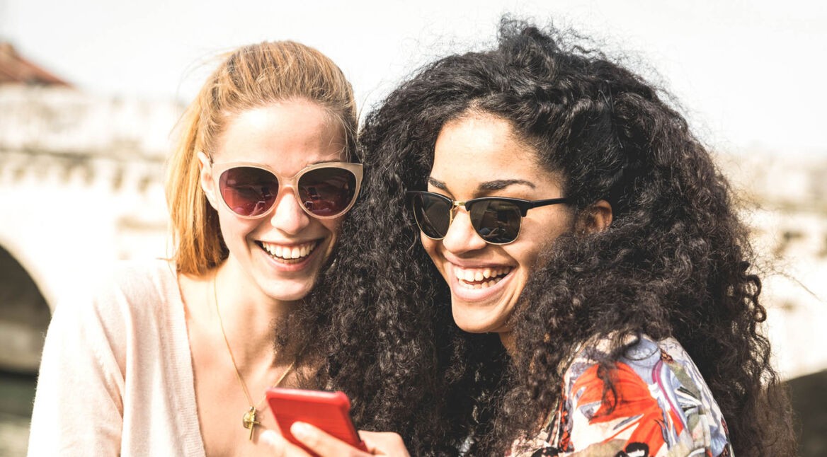 Zwei Freundinnen schauen aufs Smartphone.