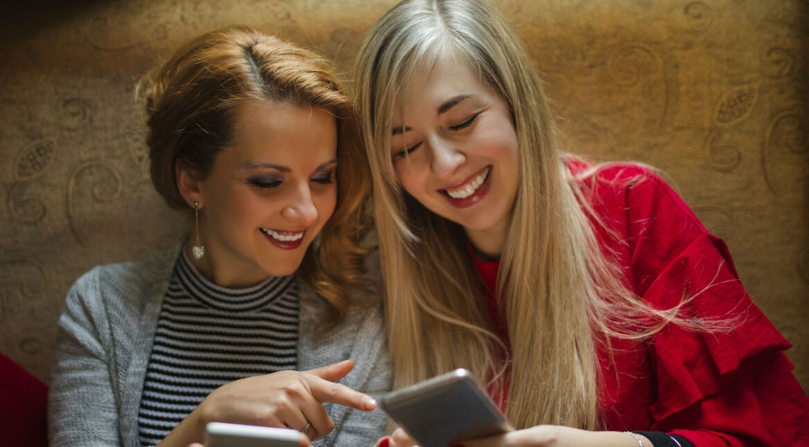 Freundinnen vergleichen ihre Smartphones miteinander.