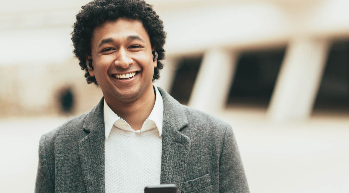 Junger Mann trägt seine Ohrhörer und hört Musik.