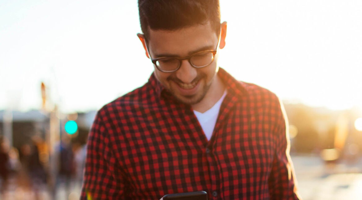 Junger Mann bearbeitet am iPhone die Anrufeinstellungen.