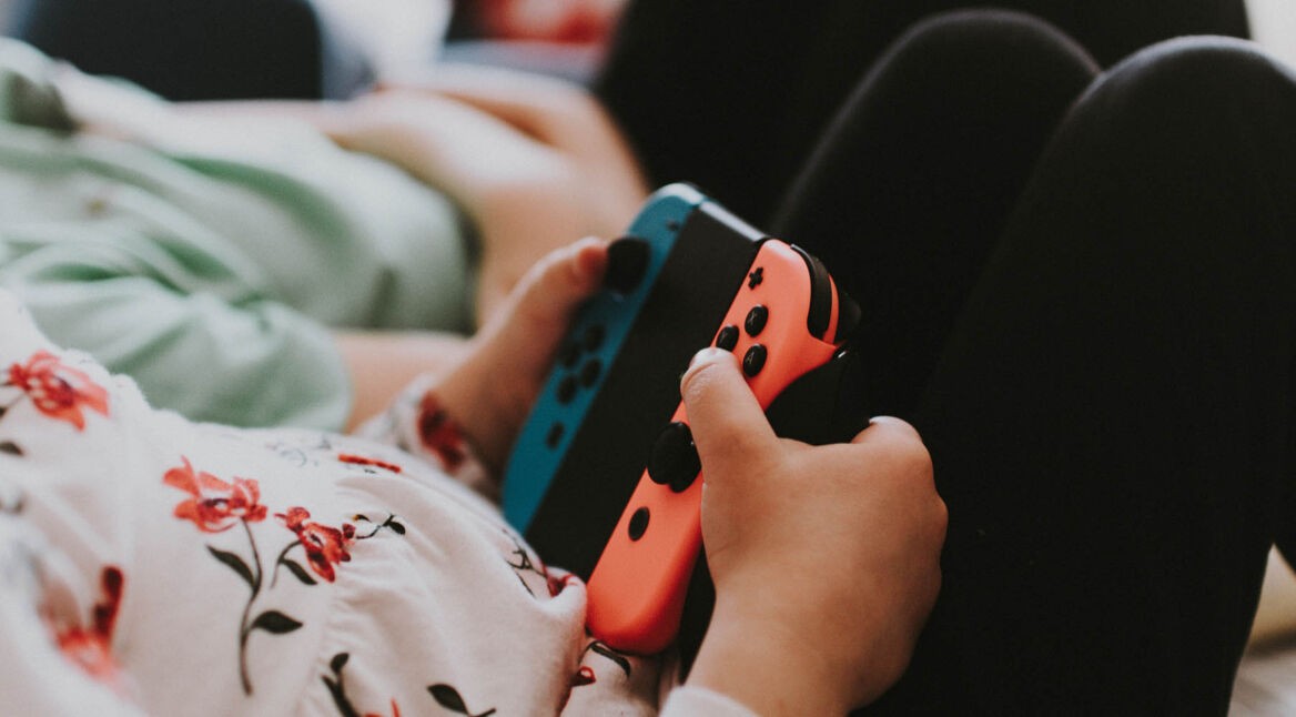 Junge Frau zockt Super Smash Bros. Ultimate mit ihren Nintendo-Switch-Controllern.