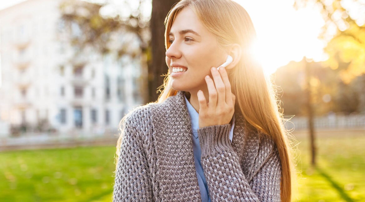 Junge Frau hört Musik von Deezer mit ihren Bluetooth-Kopfhörern.