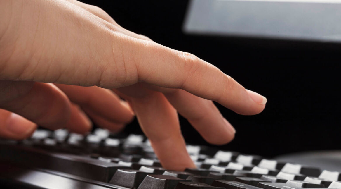 Menschliche Hand drückt Tasten auf der Tastatur.