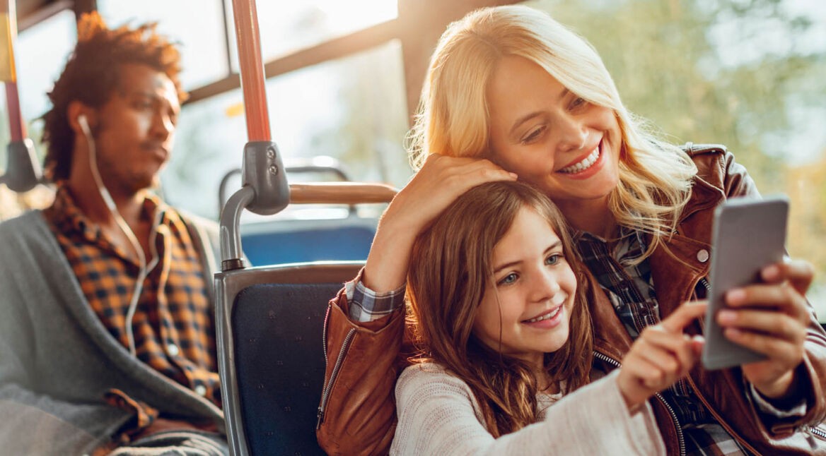 Mutter spielt mit ihrem Kind ein Minispiel am Smartphone.