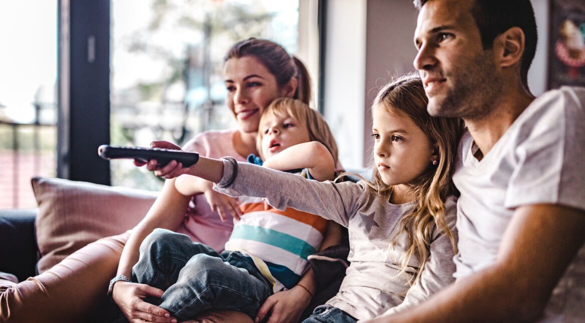 Eine junge Familie sitzt vor dem Fernseher und schaut einen Film aus den Top 10 von Netflix