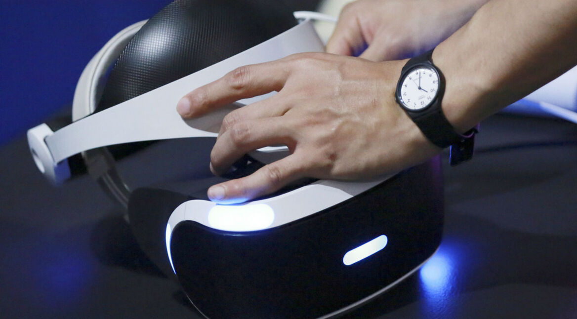 Die VR-Brille der PlayStation VR in die Hand nehmen.