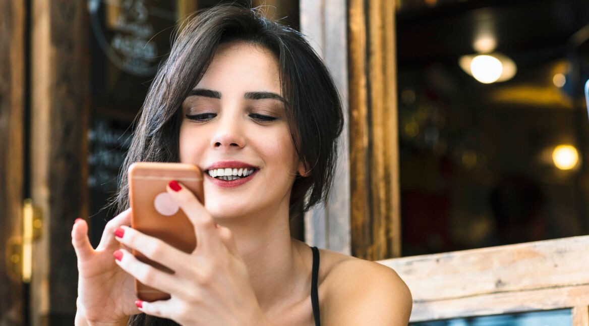 Frau schaut auf ihr Smartphone und entdeckt eine neue Google-Assistant-Funktion.