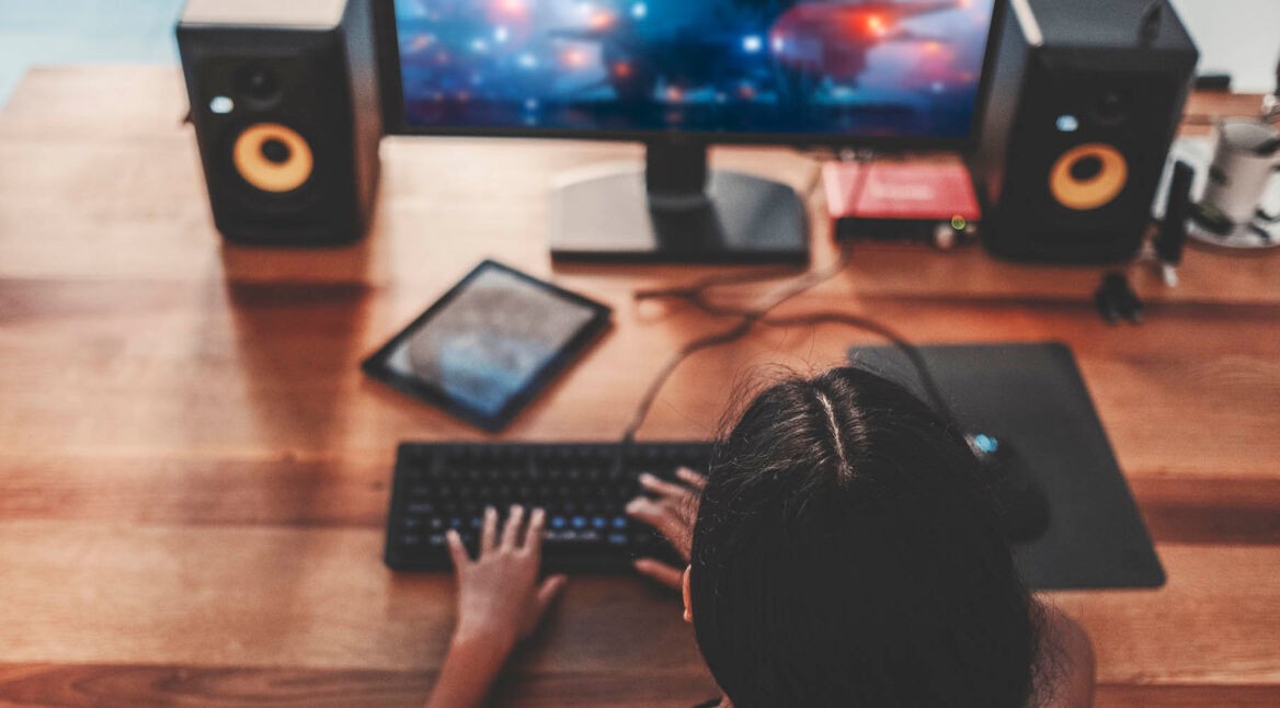 Junge Frau spielt neues PC-Spiel am Computer.