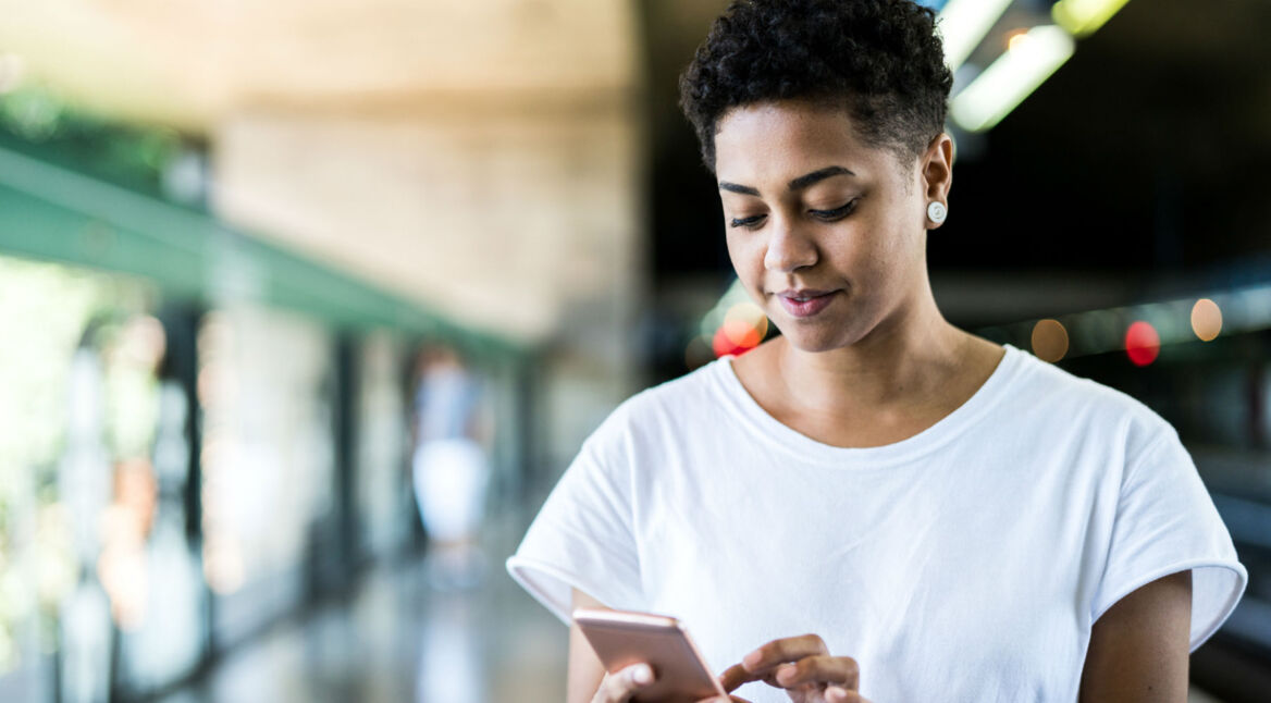 Junge Frau lädt die iOS-13-Beta auf ihr iPhone herunter.