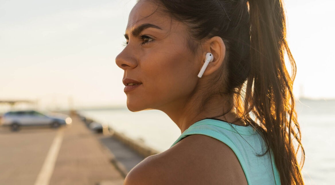 Junge Frau trägt beim Sport AirPods.