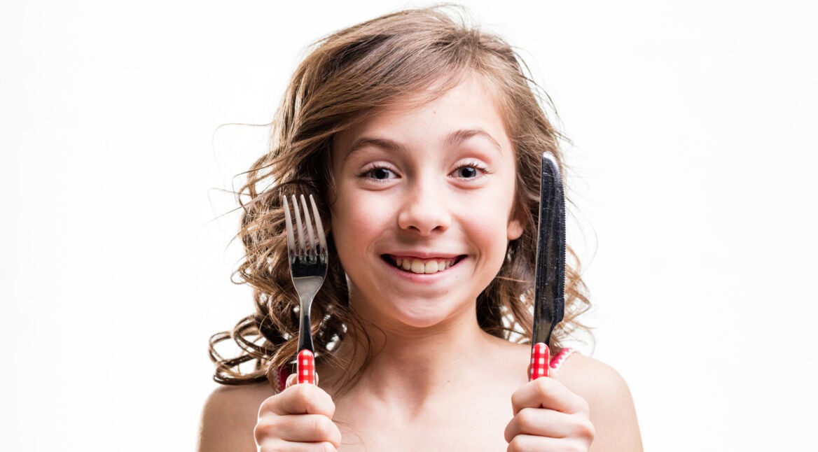 Kleines Mädchen mit Messer und Gabel
