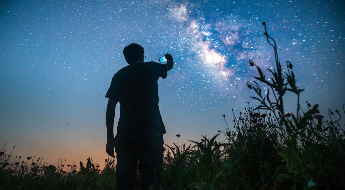 Junger Mann macht via Smartphone Fotos mit Langzeitbelichtung.