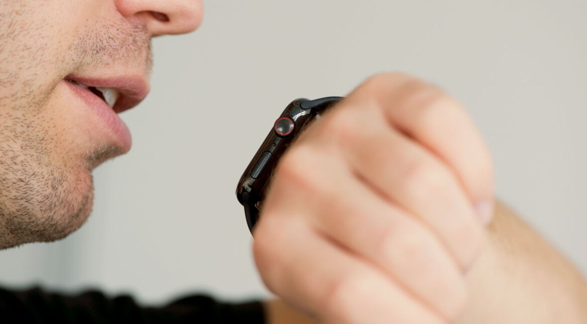 Mann hält seinen Mund nahe der Apple Watch, um Siri aufzurufen.