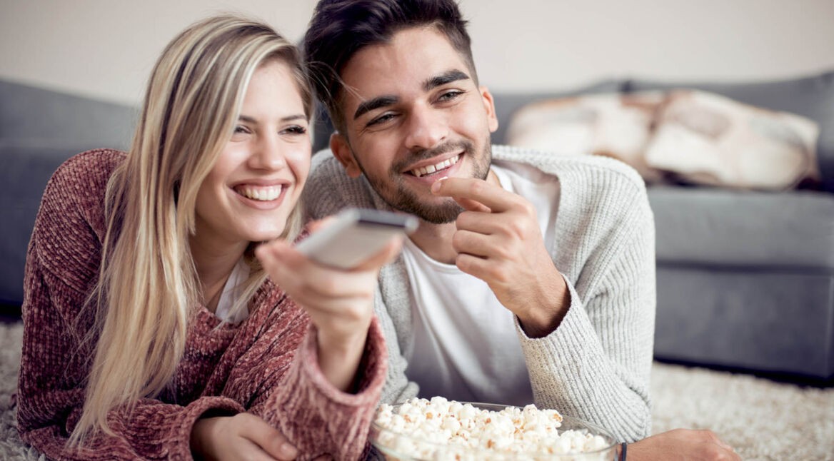 Junges Paar schaut am Fernseher neue Netflix-Serien.