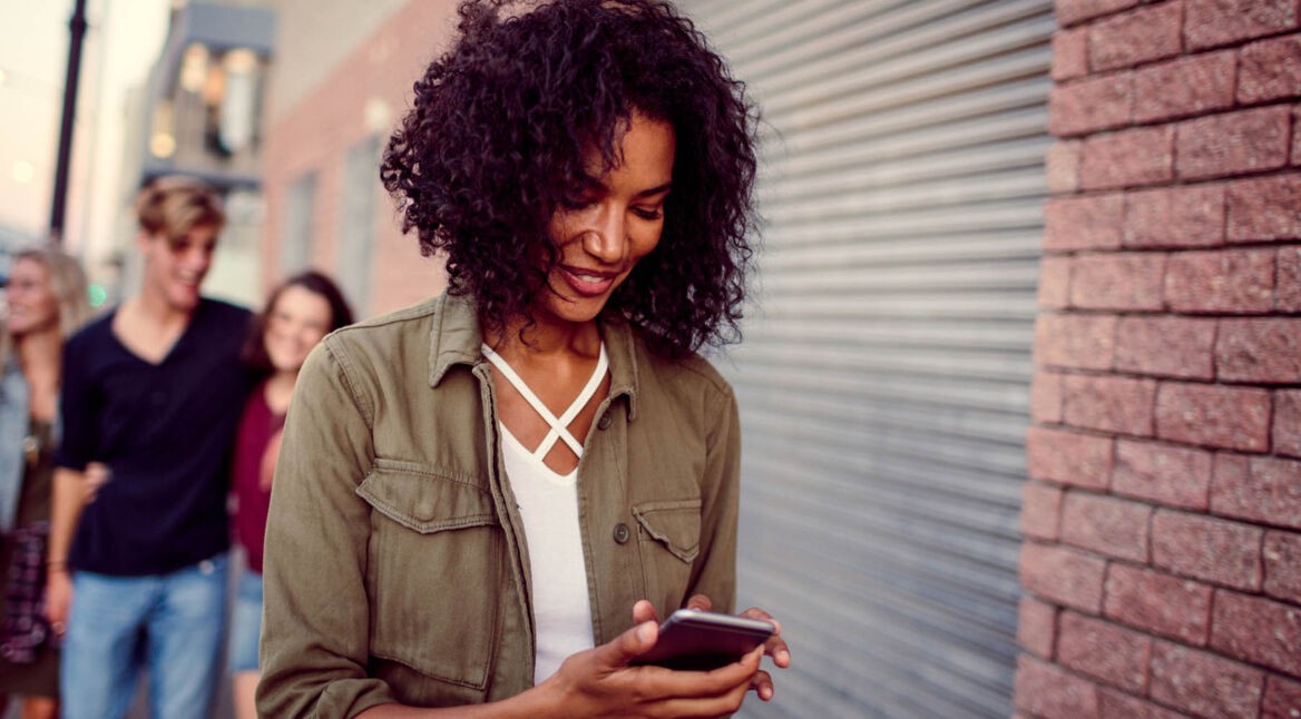 Frau liest sich am Smartphone Tipps für Threema durch.