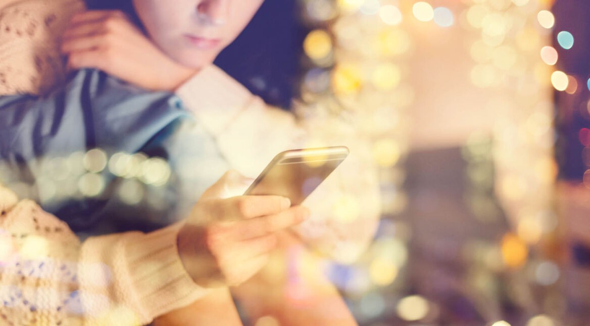 Junge Frau hält ihr iPhone in der Hand, das via iCloud-Backup wiederhergestellt wird.