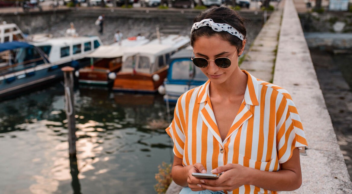 Junge Frau schaut auf ihr Handy, mit dem sie eine Webseite sperrt.