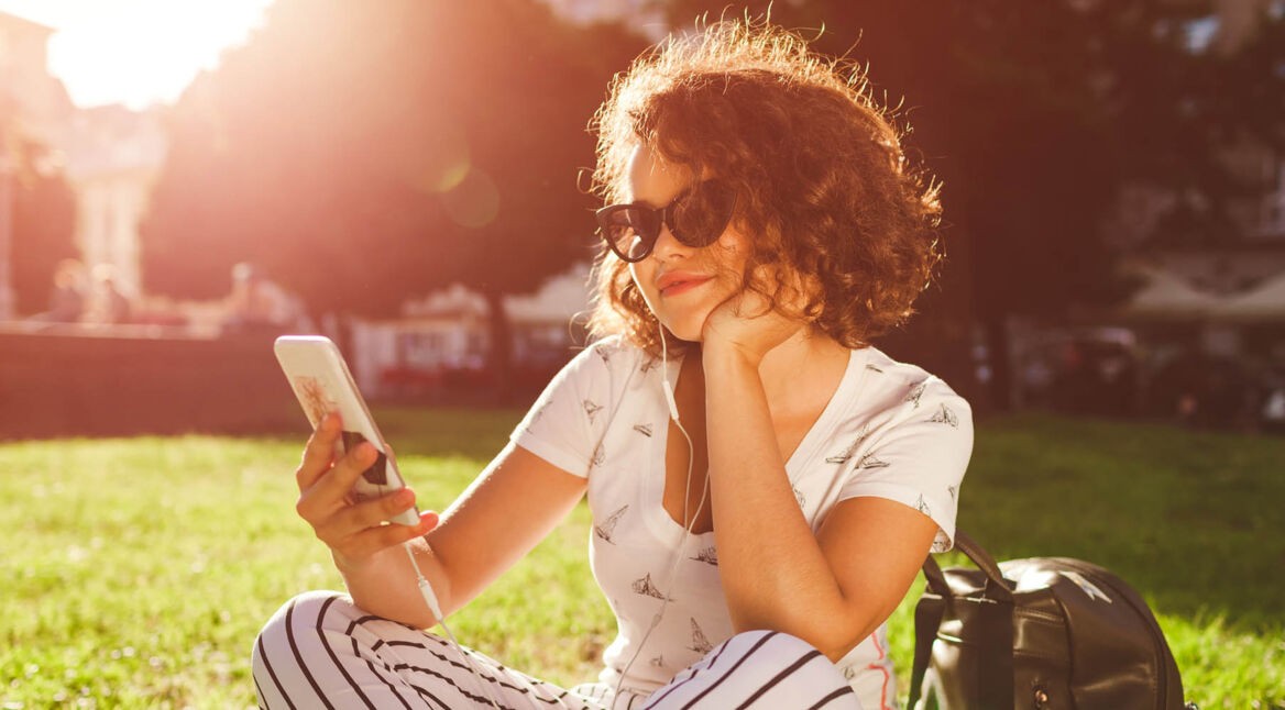 Junge Frau ändert die Deezer-Sprache am Smartphone.