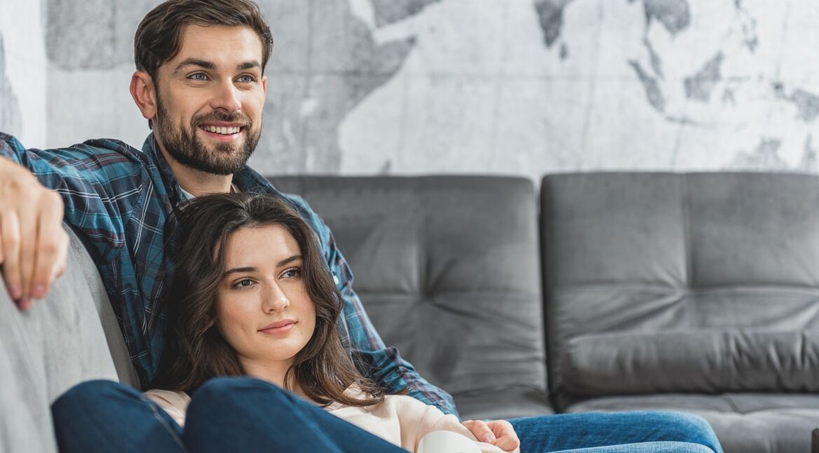 Junges Paar sitzt auf der Couch und schaut „Baby Ballroom“