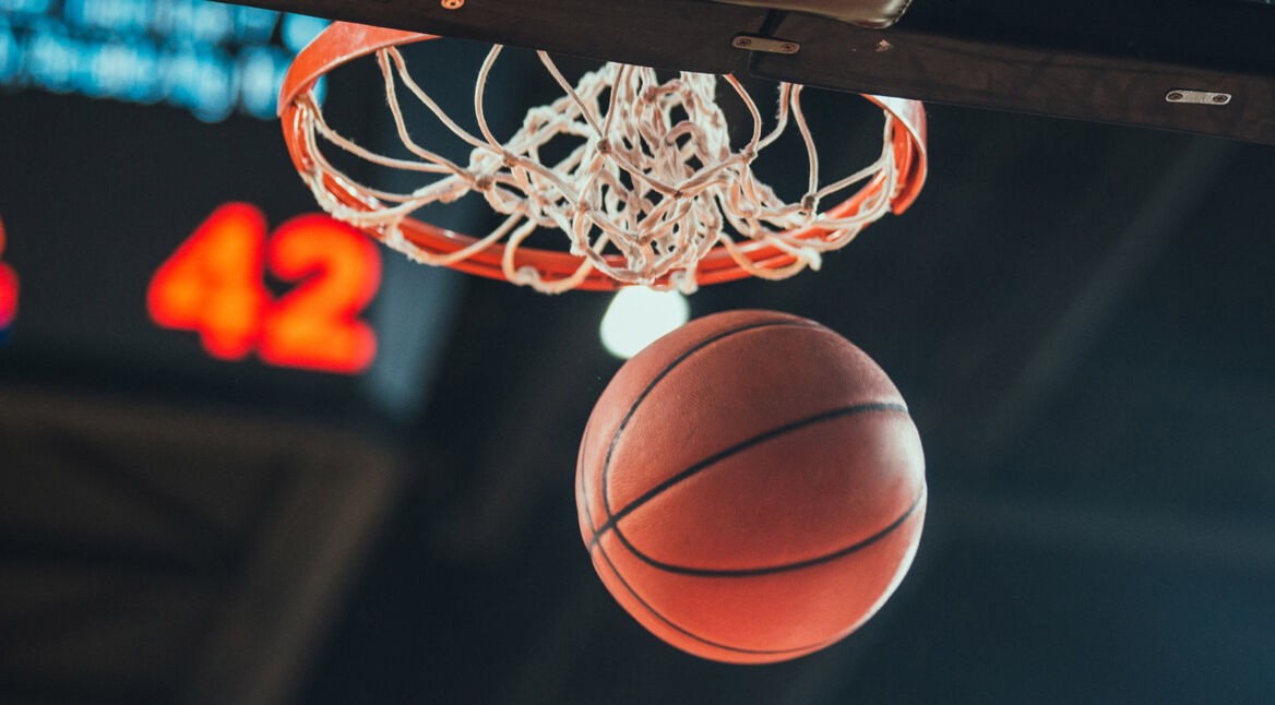 In der NBA den Basketball in den Korb werfen.