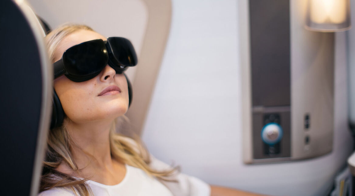 Frau mit VR-Headset nutzt Virtual Reality im Flugzeug VR