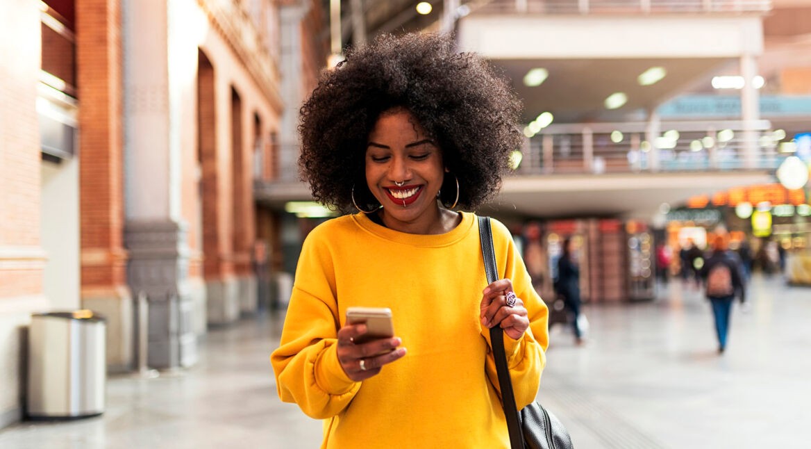 Frau lächelt ihr Smartphone an, da sie ihr Threema-Problem gelöst hat.