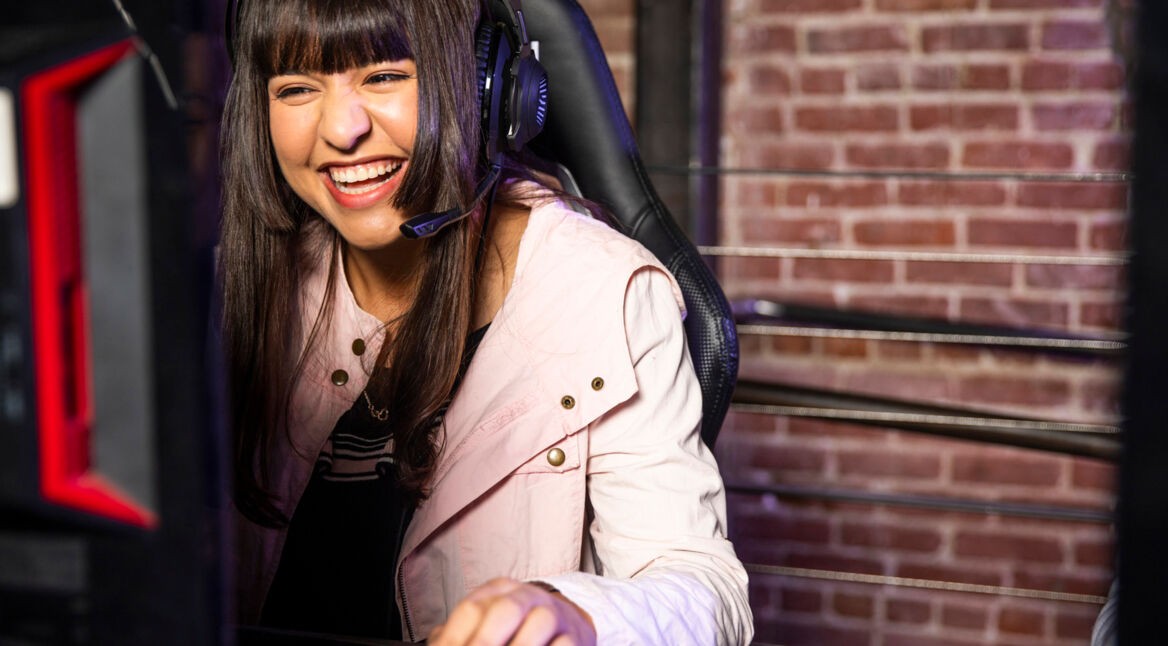 Junge Frau zockt Heartstone-Erweiterung am PC.