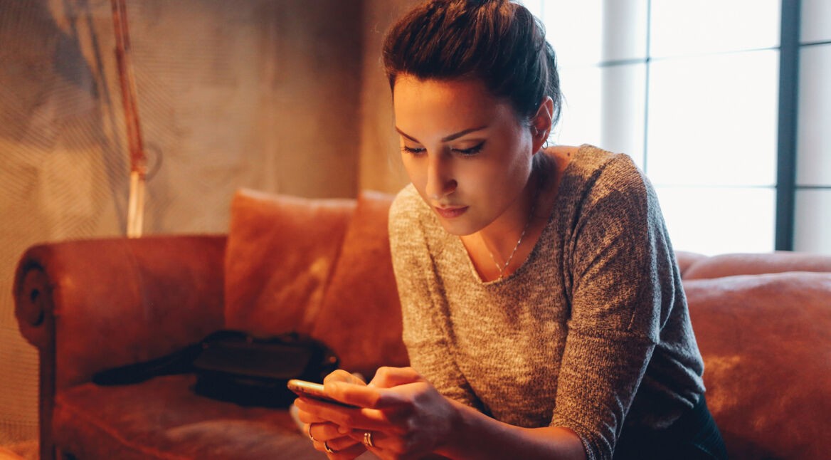 Junge Frau auf Sofa teilt eine Instagram-Story