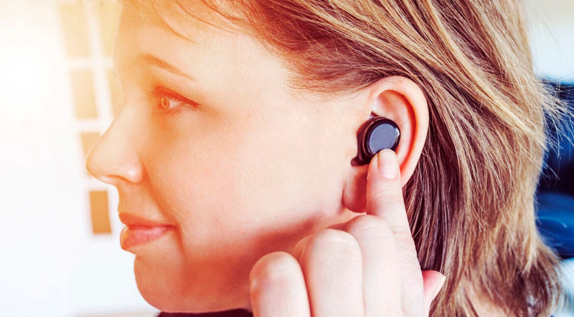 Junge Frau hört Musik über ihre Bluetooth-Kopfhörer.