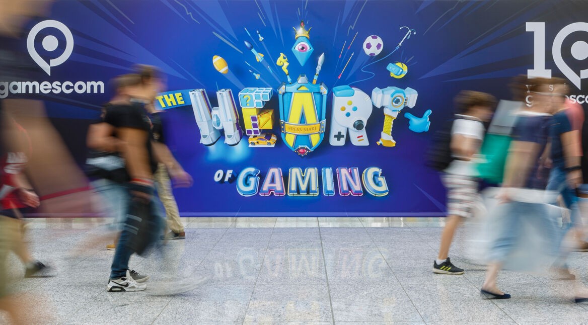 Menschen gehen an Gamescom 2019 Plakat vorbei. Foto: Koelnmesse GmbH, Andreas Hagedorn