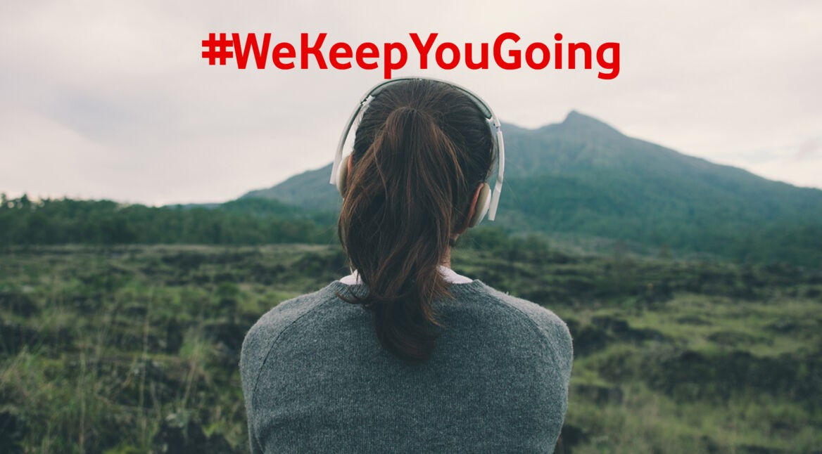 Frau mit Köpfhörern hört Reise-Poscasts und blick dabei in die Landschaft