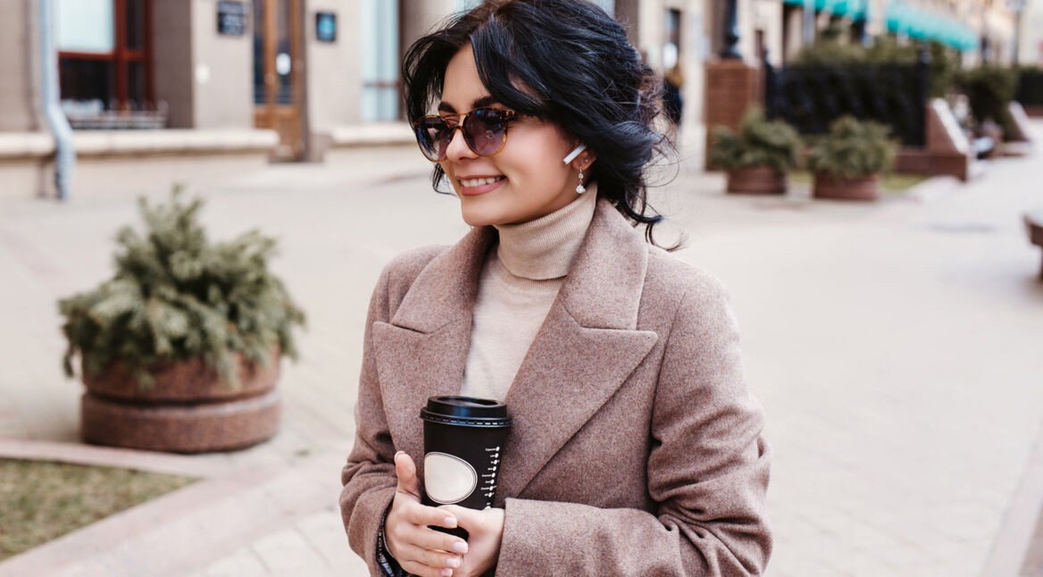 Junge Frau hört Musik über ihre True-Wireless-Kopfhörer.