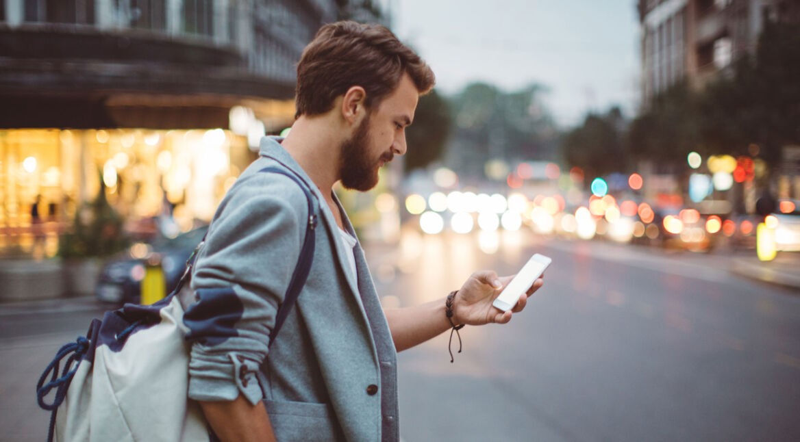 Mann mit Rucksack in der Stadt schaut auf sein Smartphone - V-Multi-Tracker