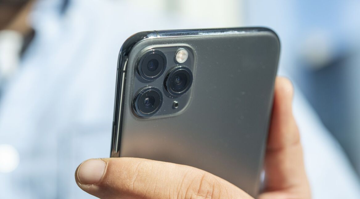 Mann drückt eine Taste am iPhone 11, um das Gerät auszuschalten.