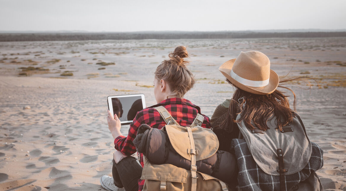 Zwei Mädchen mit Tablet am Strand