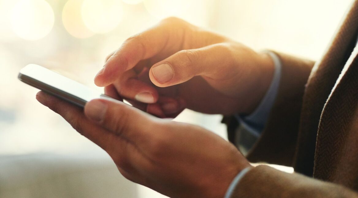 Junger Mann tippt auf das Display seines iPhone 11.