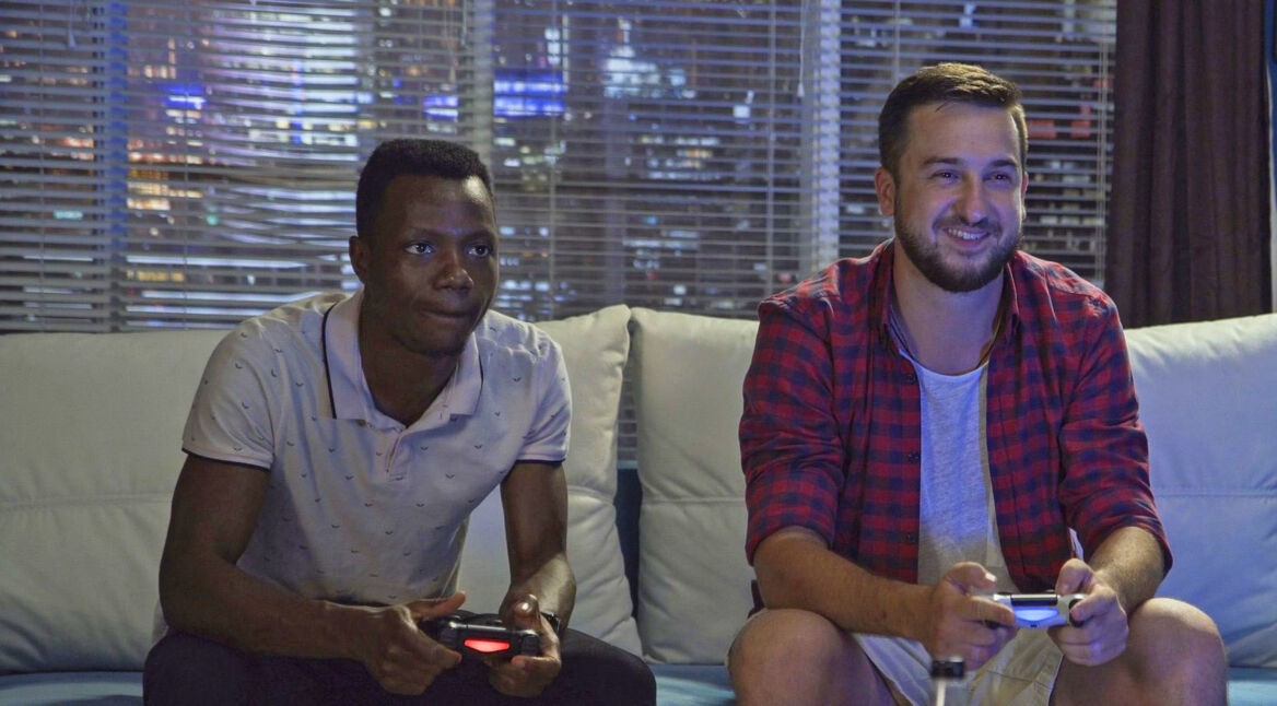 Zwei Männer spielen mit ihren Controllern ein neues PS4-Spiel.