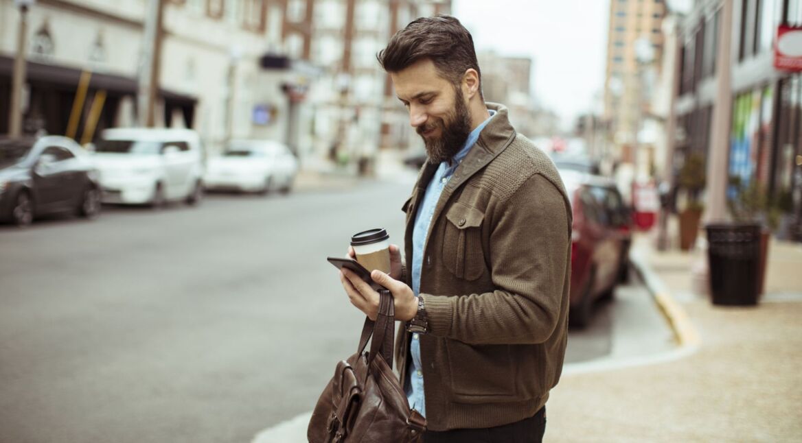 Mann schaut auf das Smartphone in seiner Hand.