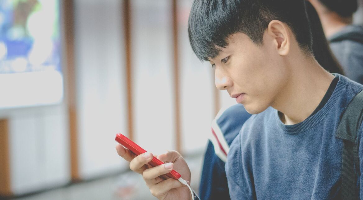 Junger Mann schaltet auf seinem Smartphone den Ambient Mode ein.