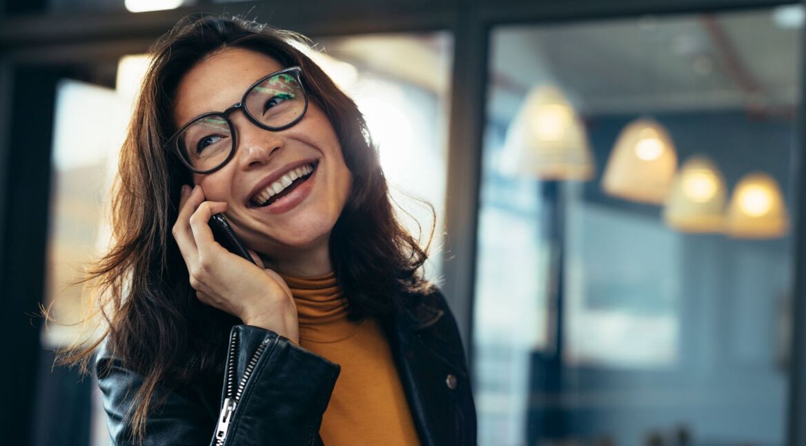 Junge Frau ruft am Smartphone via WhatsApp eine Freundin an.