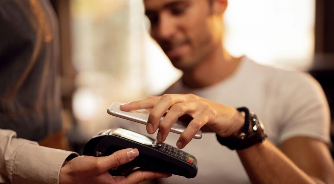 Mann zahlt kontaktlos via Google Pay auf dem Smartphone.