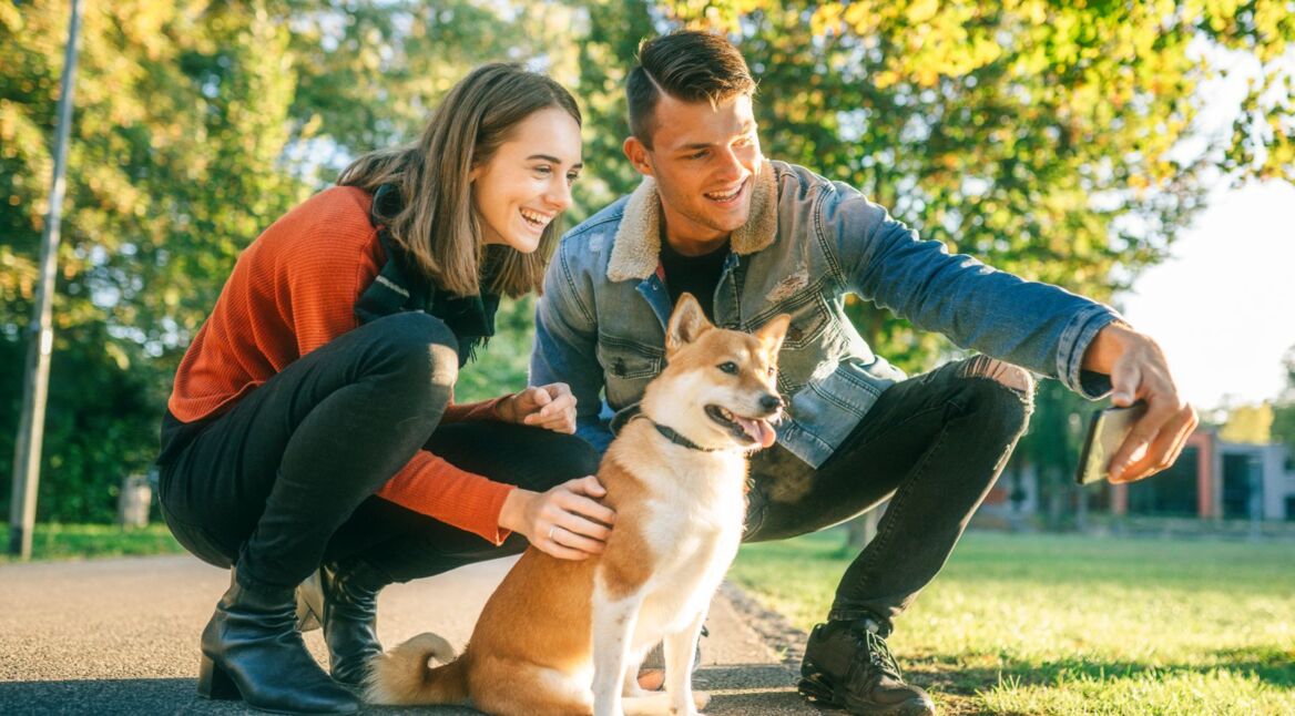 Paar nimmt Selfie mit Hund zum Teilen in Google Fotos auf.